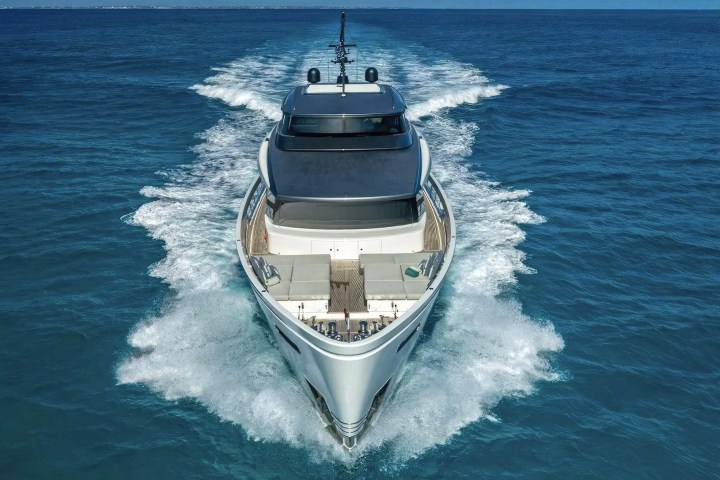 Luxury yacht cruising on open sea, leaving a trail of waves behind.
