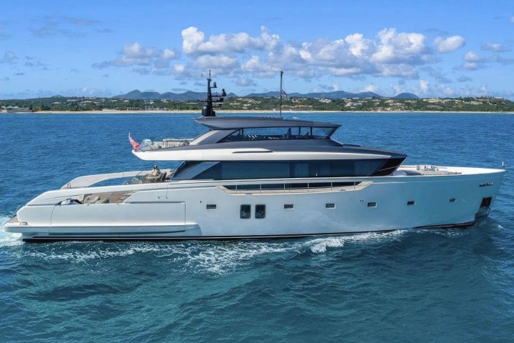 A luxury yacht sailing on calm blue water with a distant shoreline in the background.