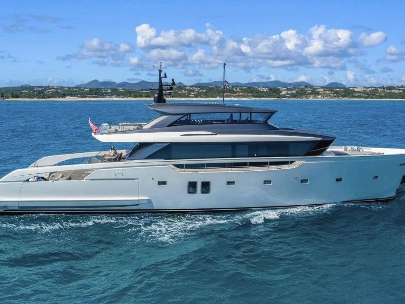 A luxury yacht sailing on calm blue water with a distant shoreline in the background.