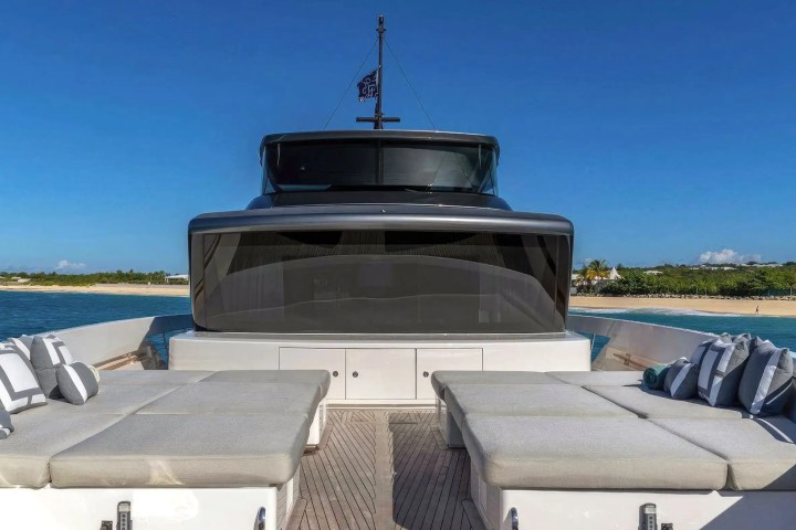 View from a yacht's deck towards a beach, with cushions and clear blue sky.