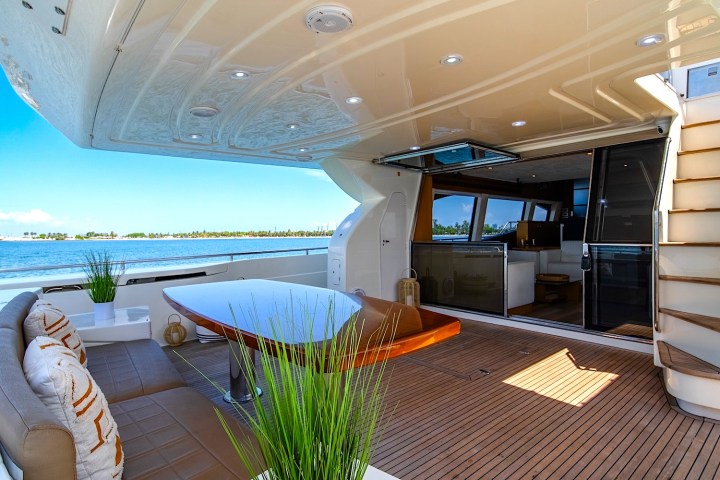Luxury yacht deck with table, chairs, stairs, and ocean view.