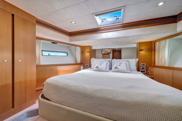Luxurious boat cabin with a double bed, skylight, and wood paneling.