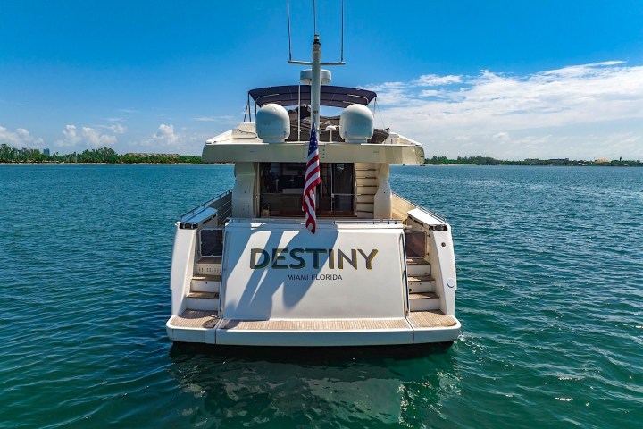 Back view of yacht 'Destiny' with US flag, ocean, and clear sky.