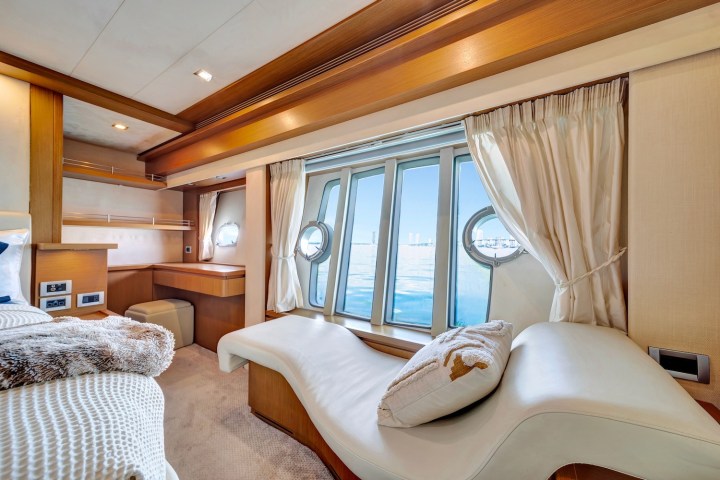Luxurious yacht cabin with a large window, chaise lounge, and bed overlooking the ocean.