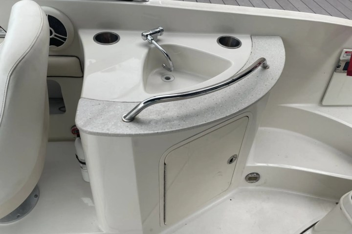 Boat interior with a small sink, faucet, and storage cabinet.