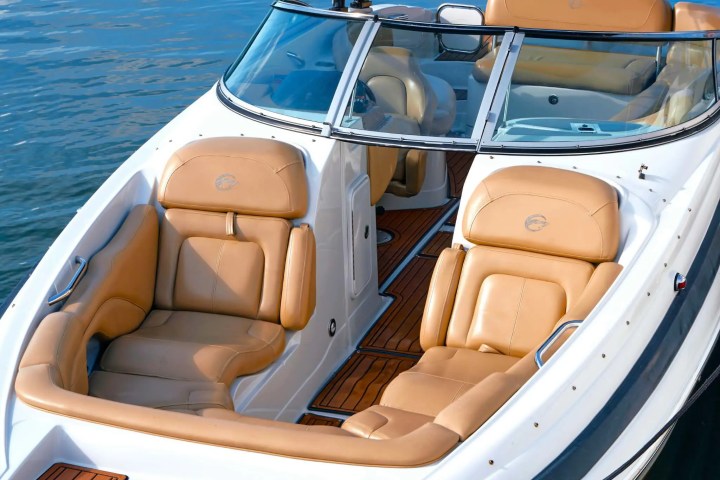 Luxury boat interior with tan leather seats and teak flooring, docked on calm water.