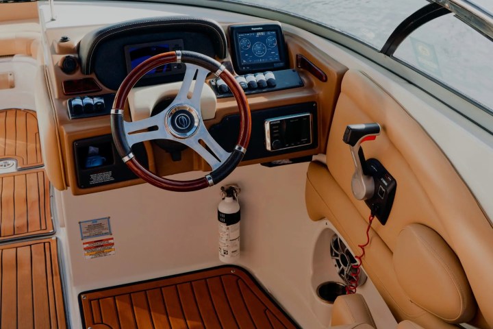 Boat cockpit with a steering wheel, dashboard, and wooden floor.