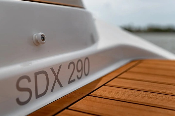 Close-up of a boat with 'SDX 290' on the hull and brown wooden deck.