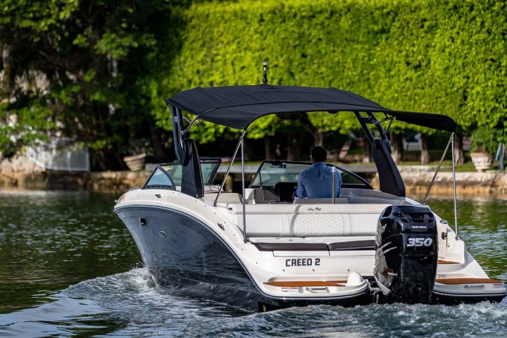 A motorboat named Creed 2 with a canopy is cruising on calm water.