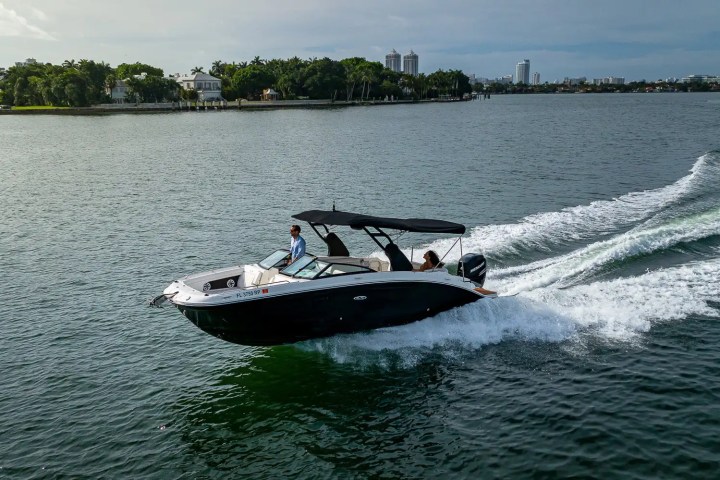 A motorboat cruising on a lake with a city skyline in the background.