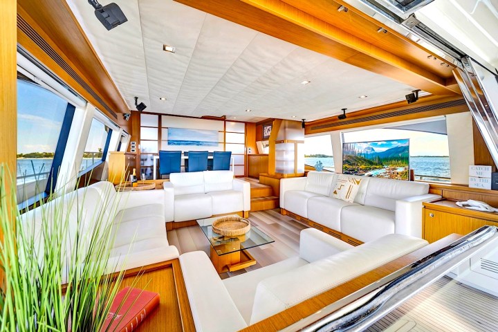 Luxurious yacht interior with white sofas, large windows, and a view of the sea.