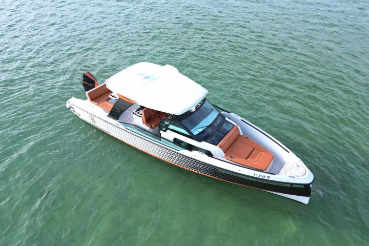 White and orange speedboat on green water, top view.