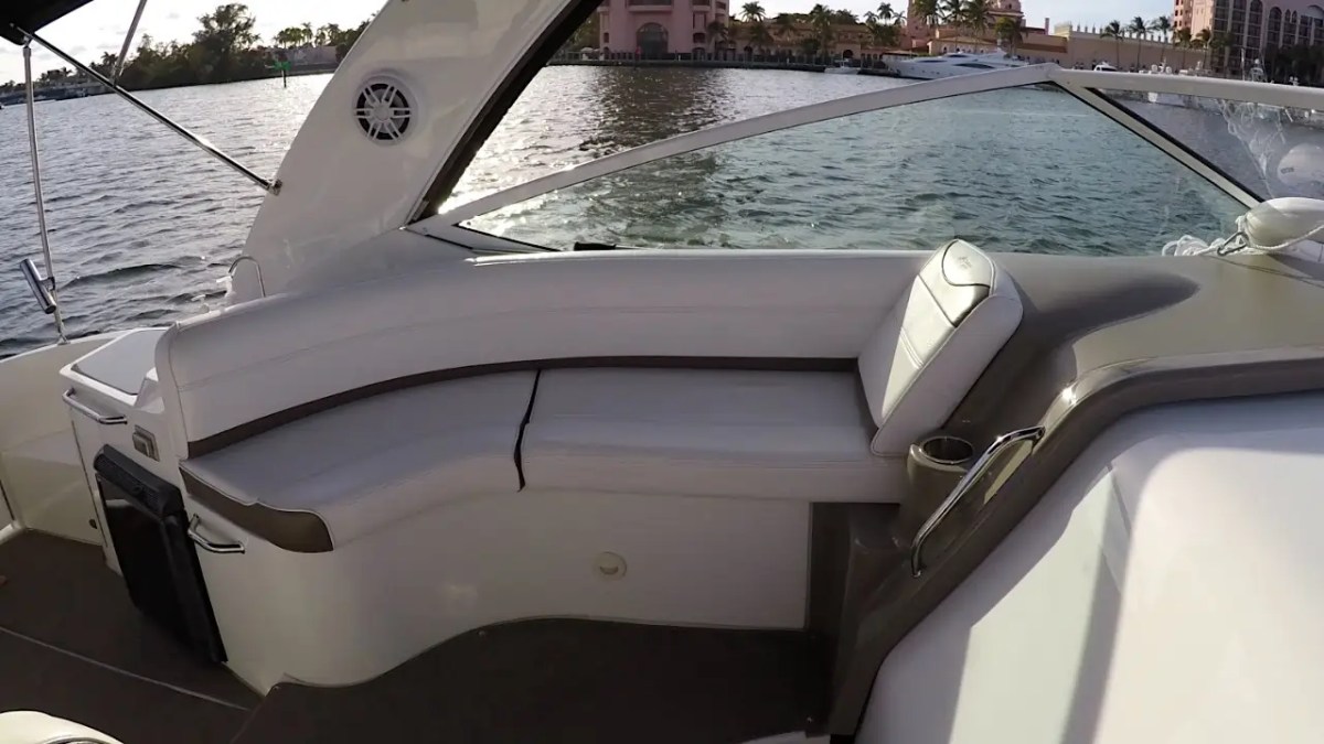 Luxury yacht seating area with white cushioned seats and a water view.