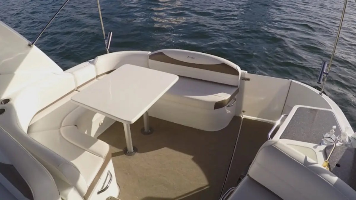 Boat deck with white seating, table, and calm water view.