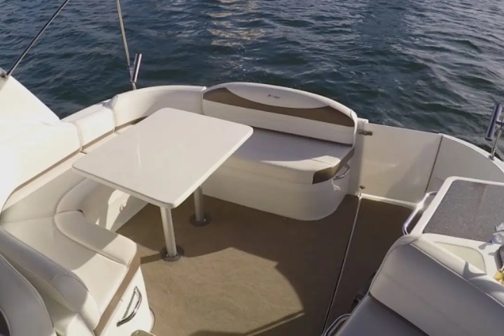 Boat deck with white seating, table, and calm water view.