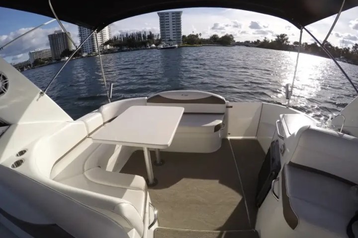 Boat seating area with table overlooking water and buildings in distance.