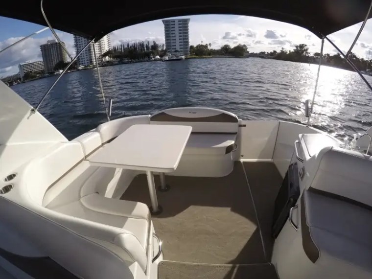 Boat seating area with table overlooking water and buildings in distance.