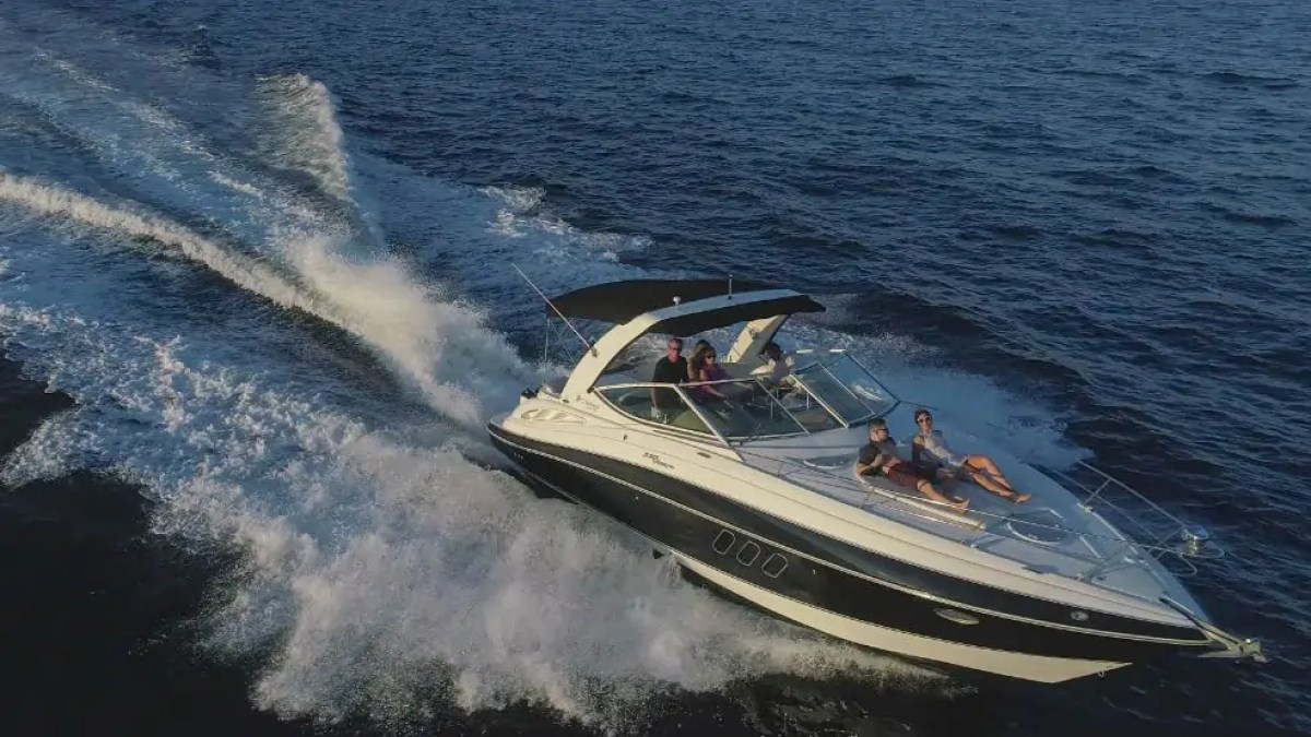 People on a speedboat cruising on open water, creating waves.