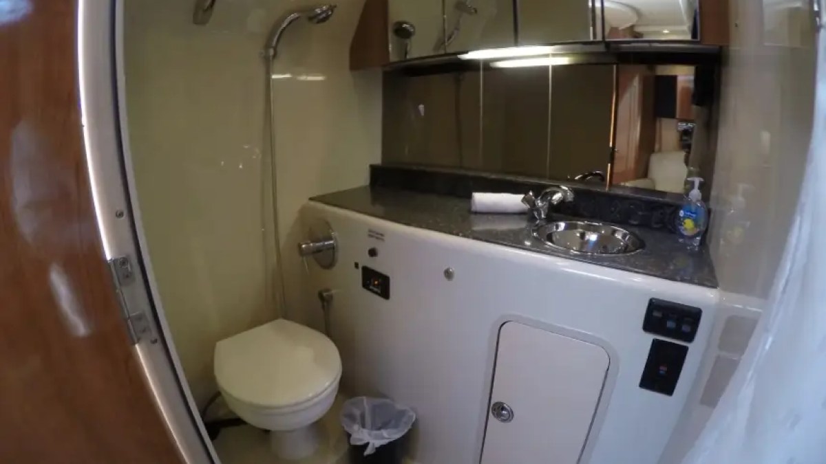 Compact RV bathroom with toilet, sink, shower, and mirrored cabinets.