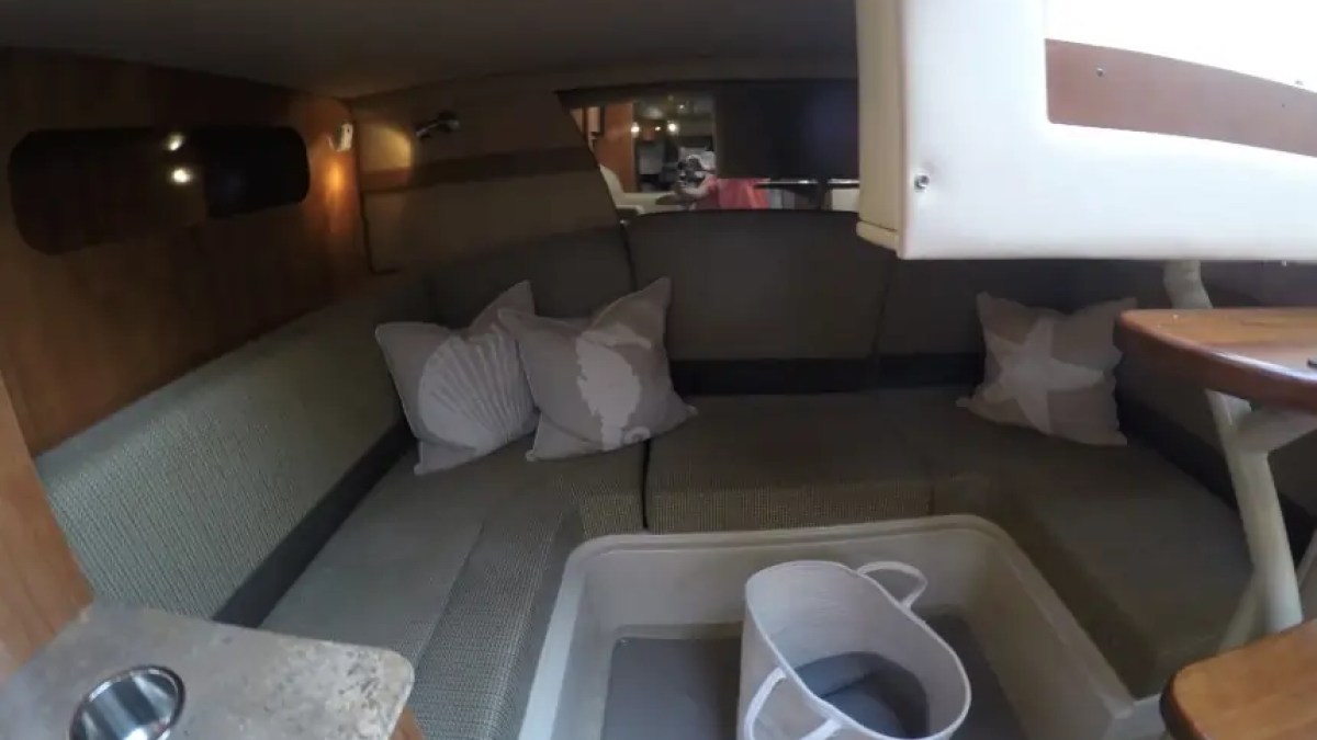 Interior of a small boat cabin with cushions and a bucket on the floor.