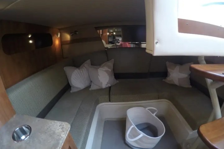 Interior of a small boat cabin with cushions and a bucket on the floor.