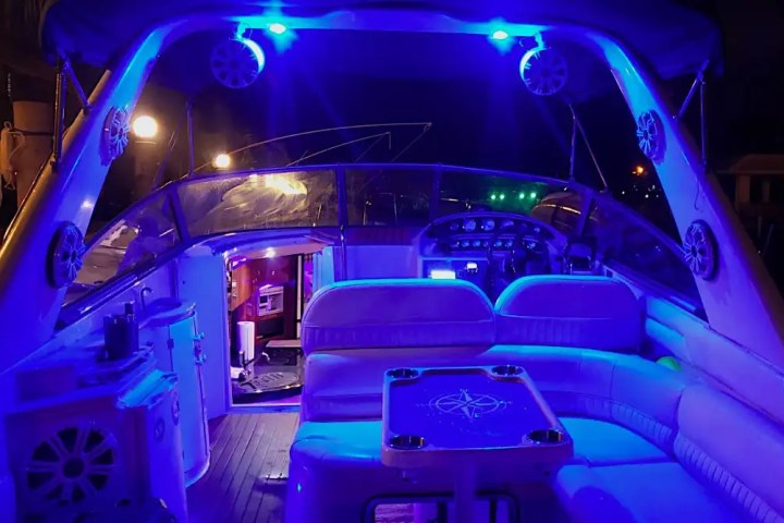 Boat interior with blue neon lights illuminating seating and control area.