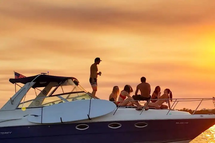 People relaxing on a boat during sunset over the water.