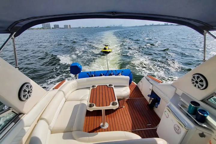 View from a boat's deck with a jet ski being towed on a sunny day.
