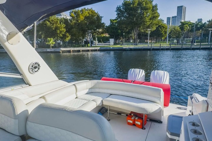 View from a boat with white seats and a canopy, overlooking a waterfront cityscape.