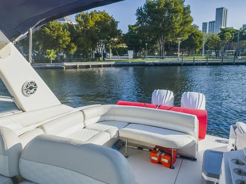 View from a boat with white seats and a canopy, overlooking a waterfront cityscape.
