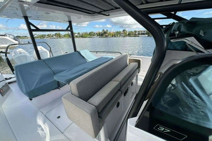 Interior of a boat with seating and water view in the background under a partially covered area.