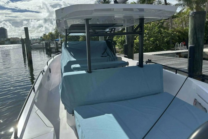 A boat with blue chair covers docked near a marina with surrounding palm trees.