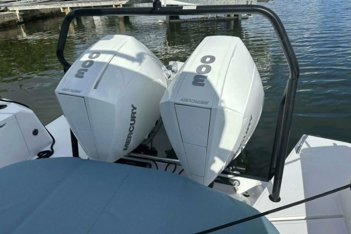 Two white outboard motors labeled '300 Mercury' mounted on a boat near water.