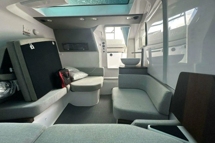 Interior of a modern yacht cabin with grey seating and a skylight.