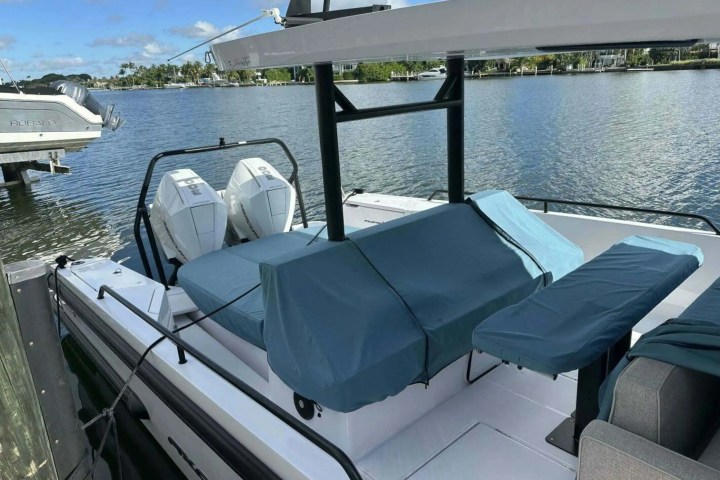 A boat docked, showing covered seats and dual outboard motors on a sunny day.