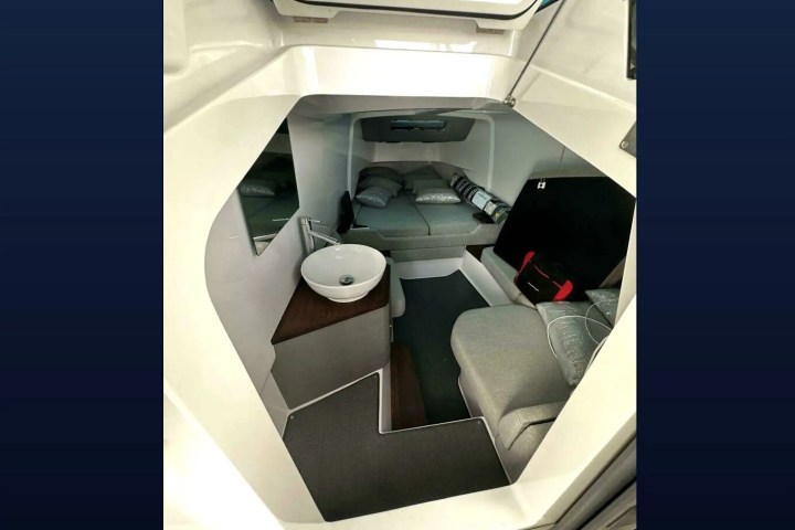 Compact cabin interior with a round sink, gray seating, and a bed.