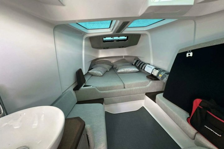 Interior of a compact modern camper with a bed, skylights, and sink.