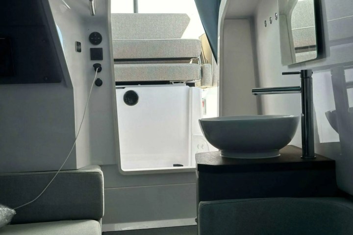 Interior of a modern boat with a sink, faucet, and seating area in minimalist design.