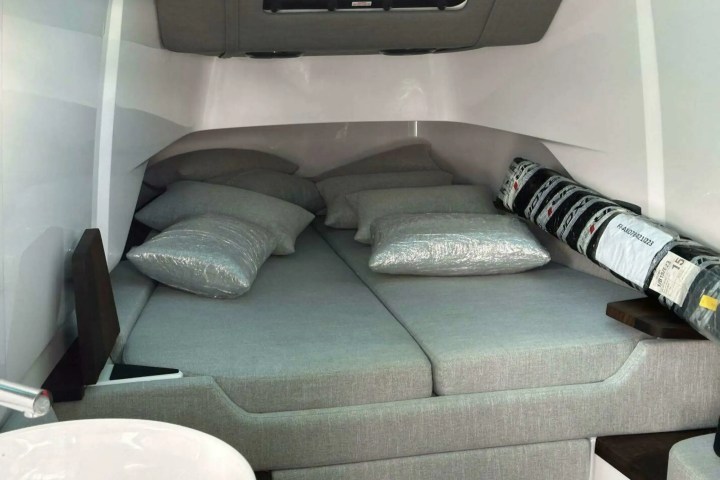 Interior of a compact boat cabin with a gray bed and cushions.