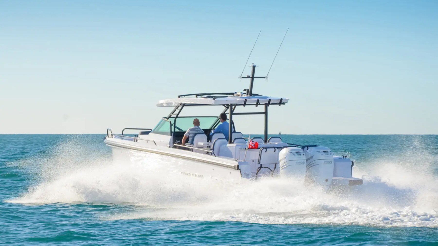 A motorboat speeding across the ocean under a clear blue sky.