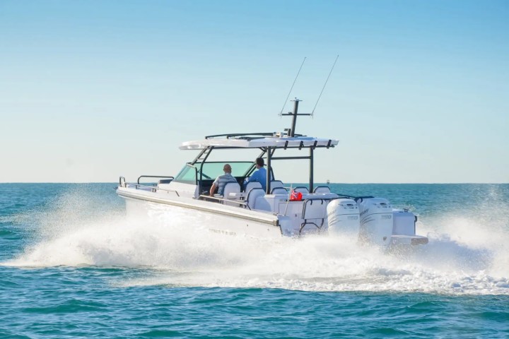 A motorboat speeding across the ocean under a clear blue sky.