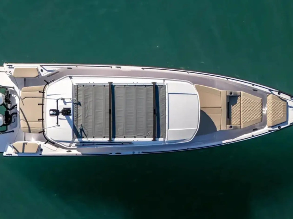 Top view of a sleek motorboat with dual engines on a calm green sea.