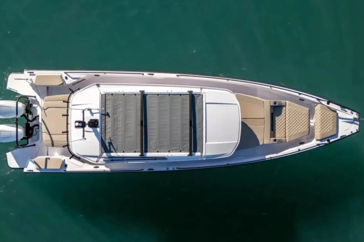 Top view of a sleek motorboat with dual engines on a calm green sea.