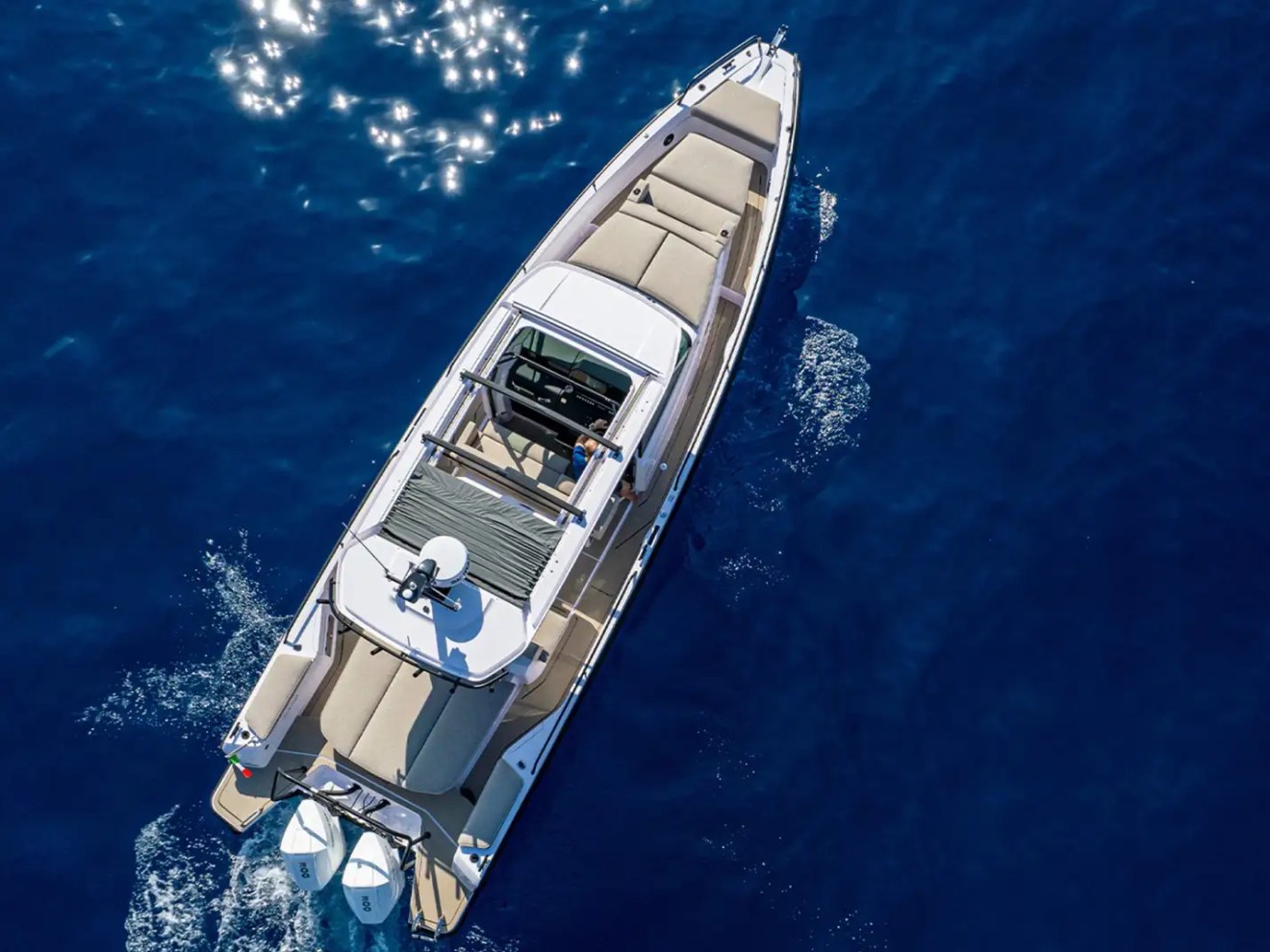 Aerial view of a motorboat with beige seats on blue ocean water.