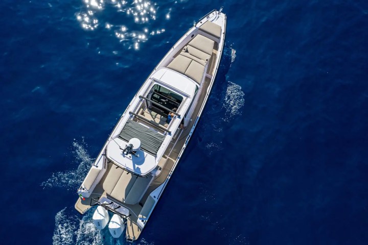 Aerial view of a motorboat with beige seats on blue ocean water.
