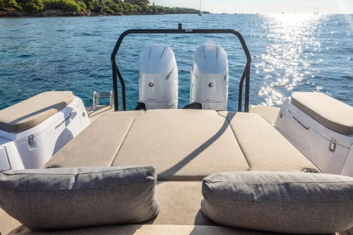 Boat deck with cushioned seats overlooking a sunny ocean view.