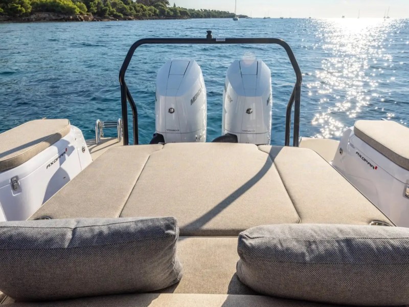 Boat deck with cushioned seats overlooking a sunny ocean view.
