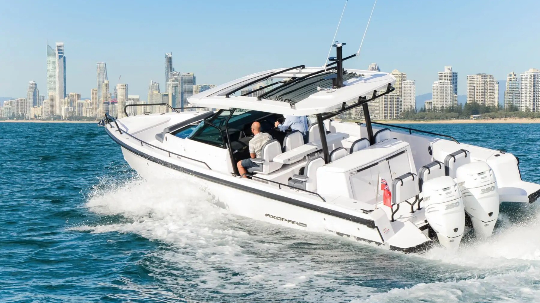 White motorboat speeding on water with city skyline in the background.