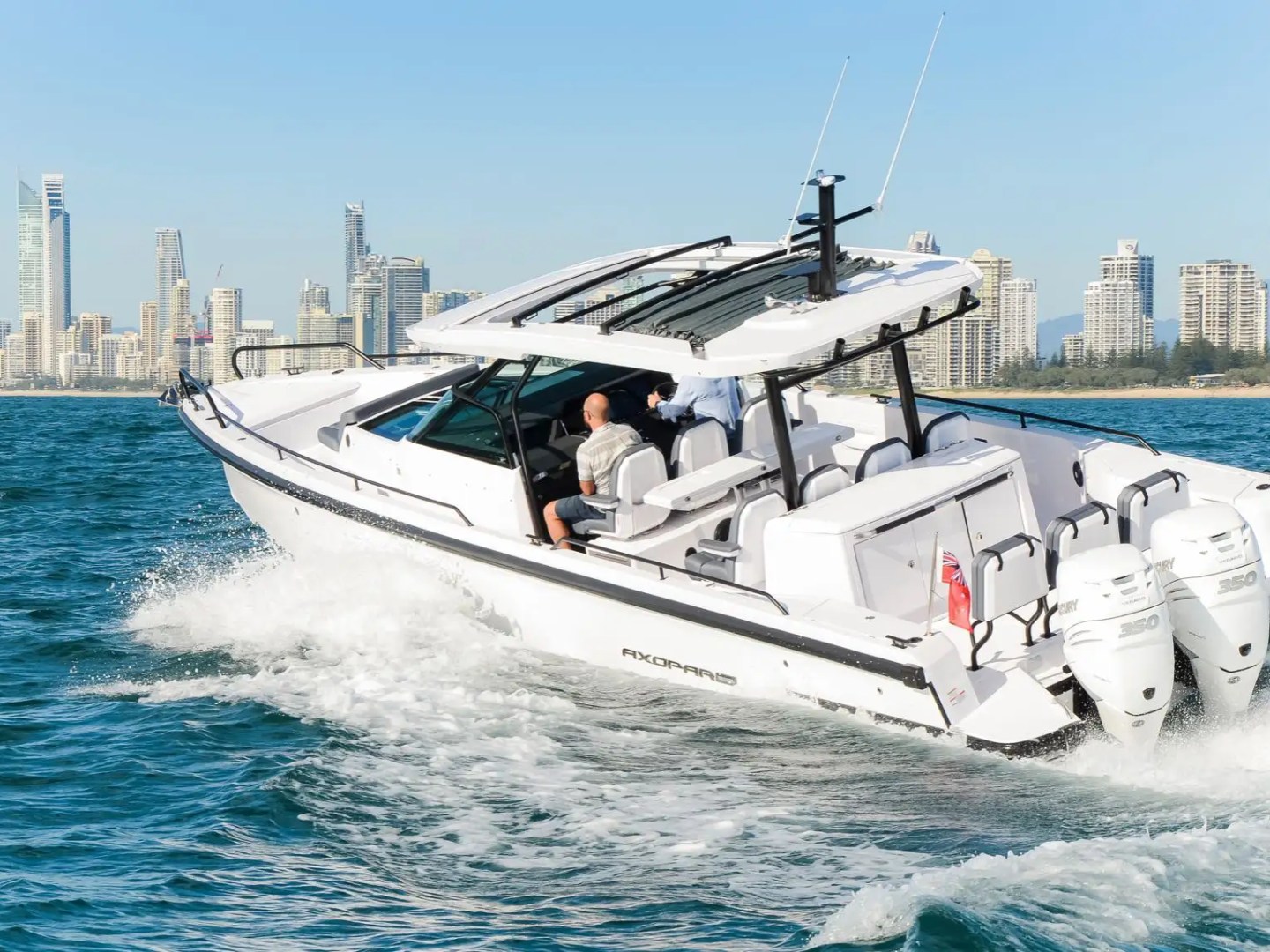 White motorboat speeding on water with city skyline in the background.