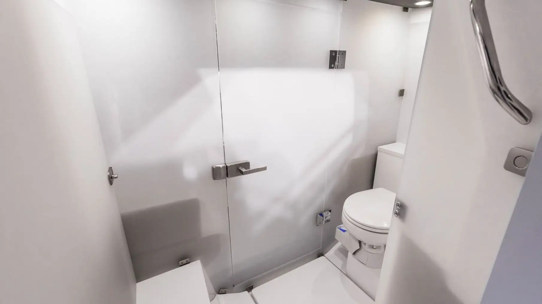 Compact white bathroom with toilet and glass door shower.